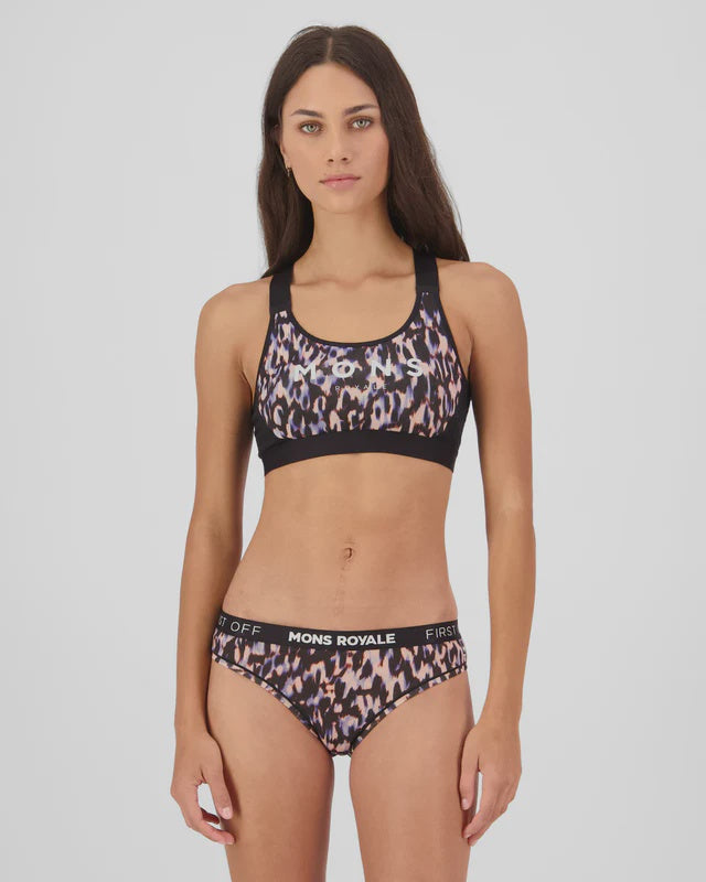 Woman wearing a leopard print sports bra and shorts with 'Mons Royale' branding on a white background