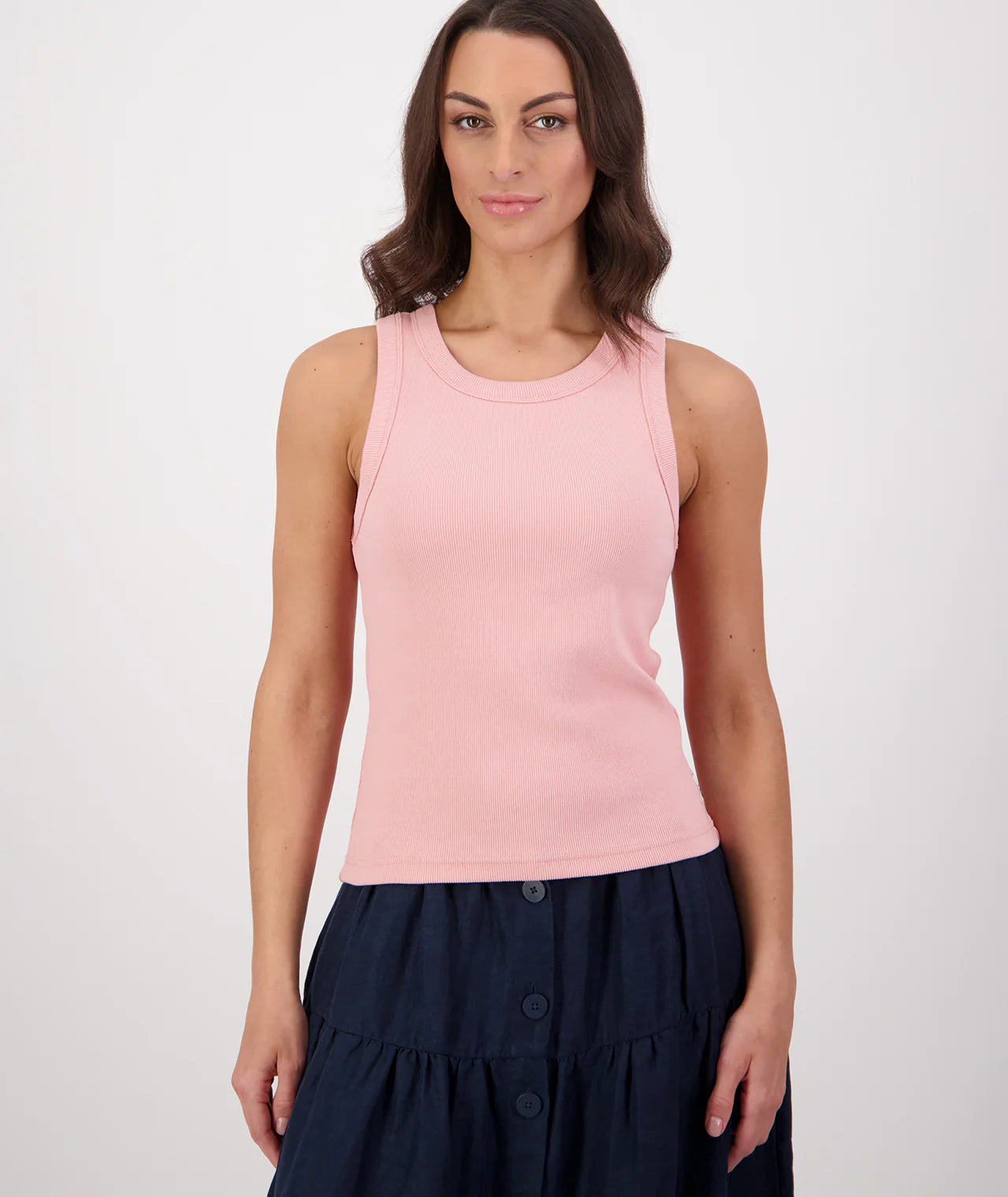 Woman wearing a pink sleeveless top and navy skirt on a white background