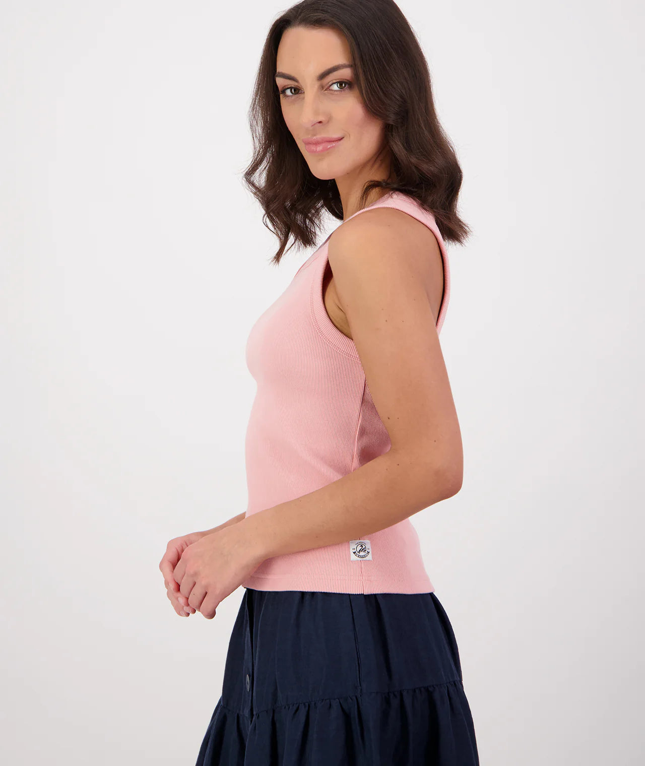 Woman wearing a pink sleeveless top with a navy skirt on a white background