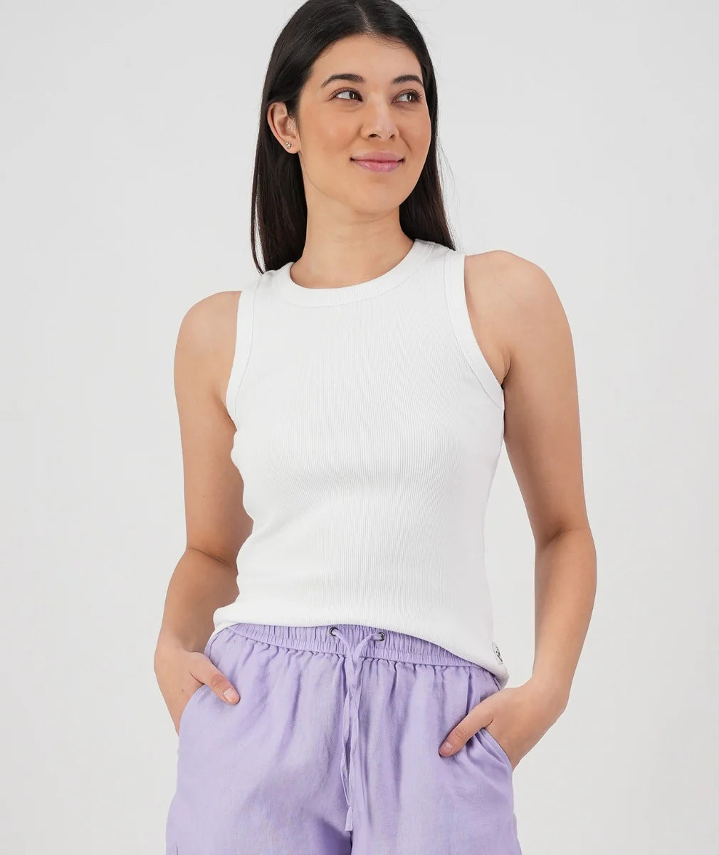Woman wearing a white sleeveless top and purple pants against a white background