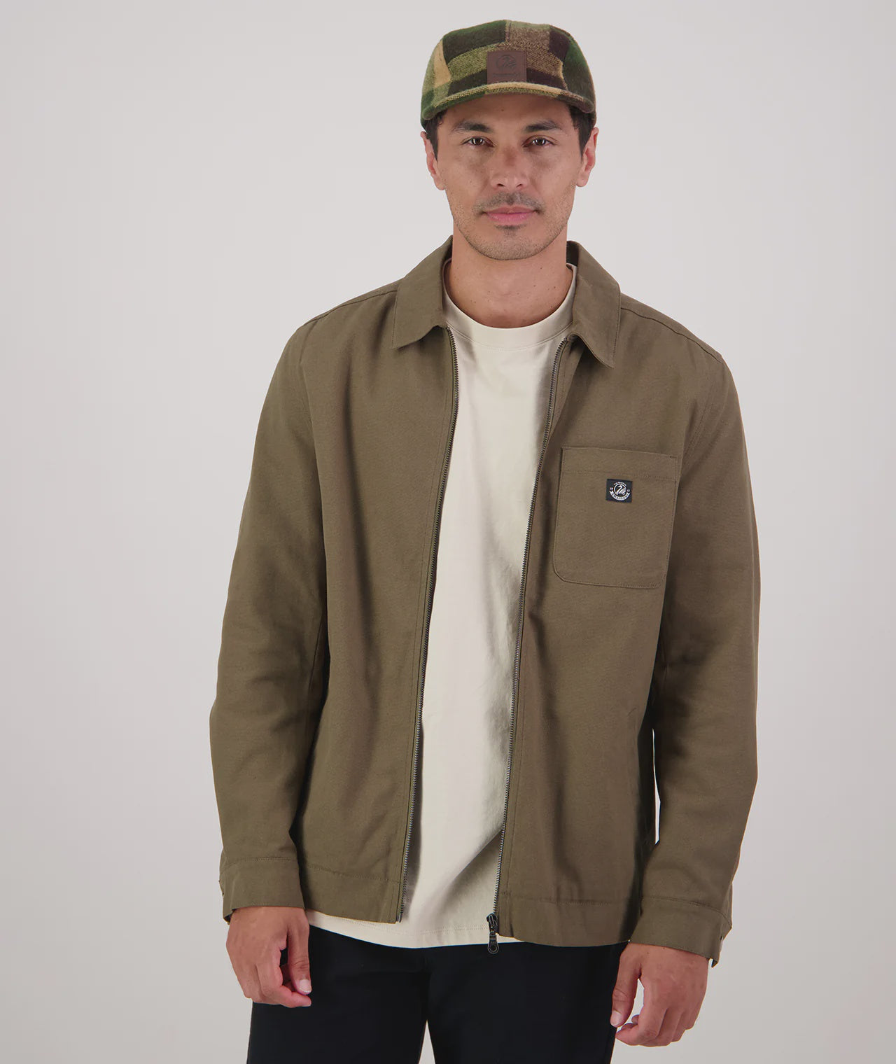 Man wearing a dark olive jacket and camouflage cap on a white background