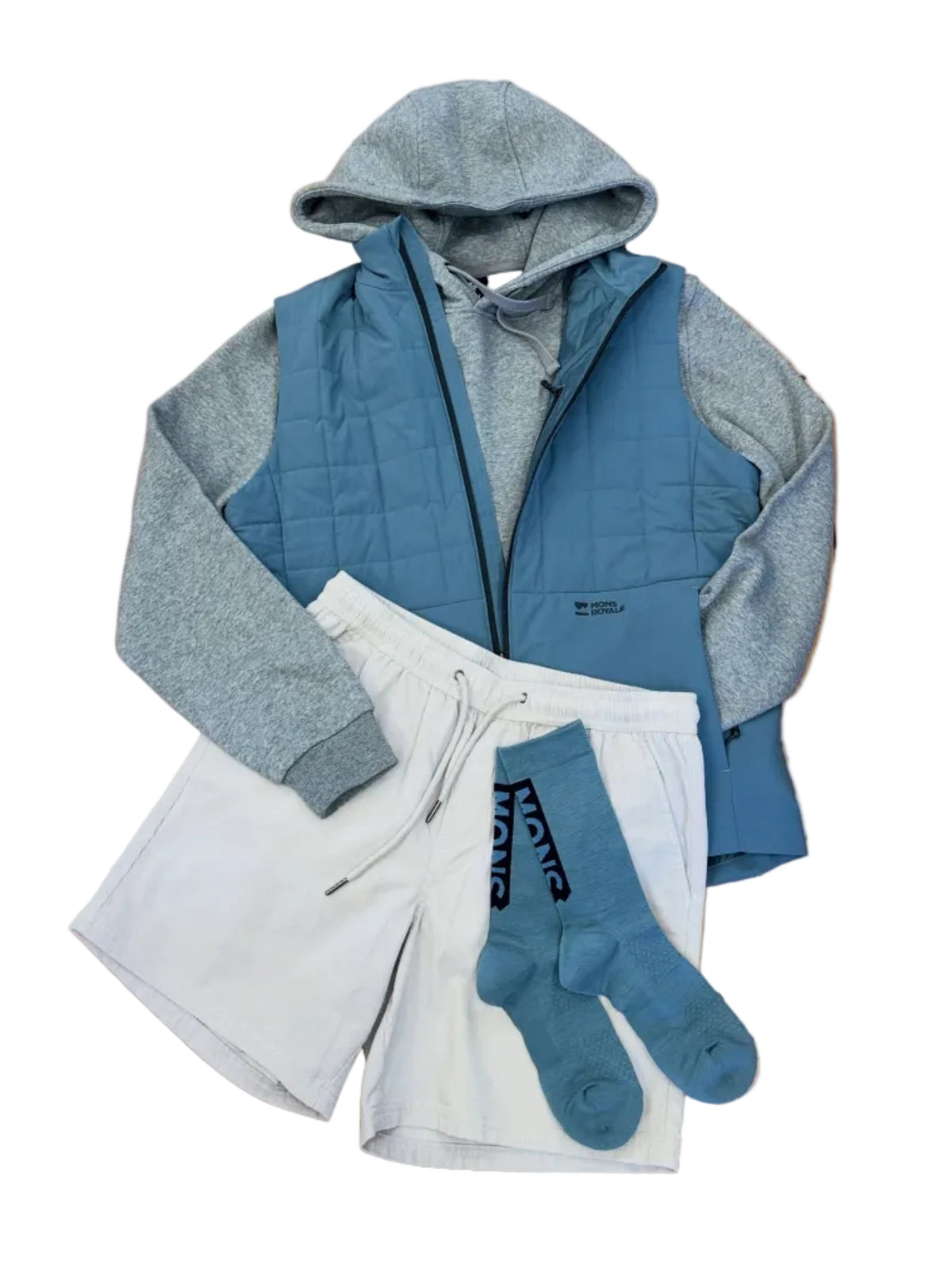 A styled flat-lay of a multi-piece loungewear set on a wooden plank floor. The set includes a slate blue and heather gray zip-up hoodie, white drawstring sweat shorts, and slate blue crew socks with black text.