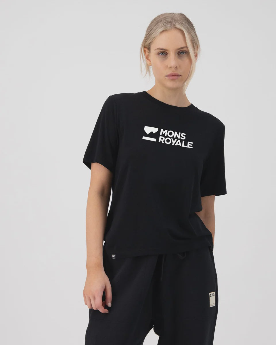Person wearing a black 'Mons Royale' t-shirt on a white background