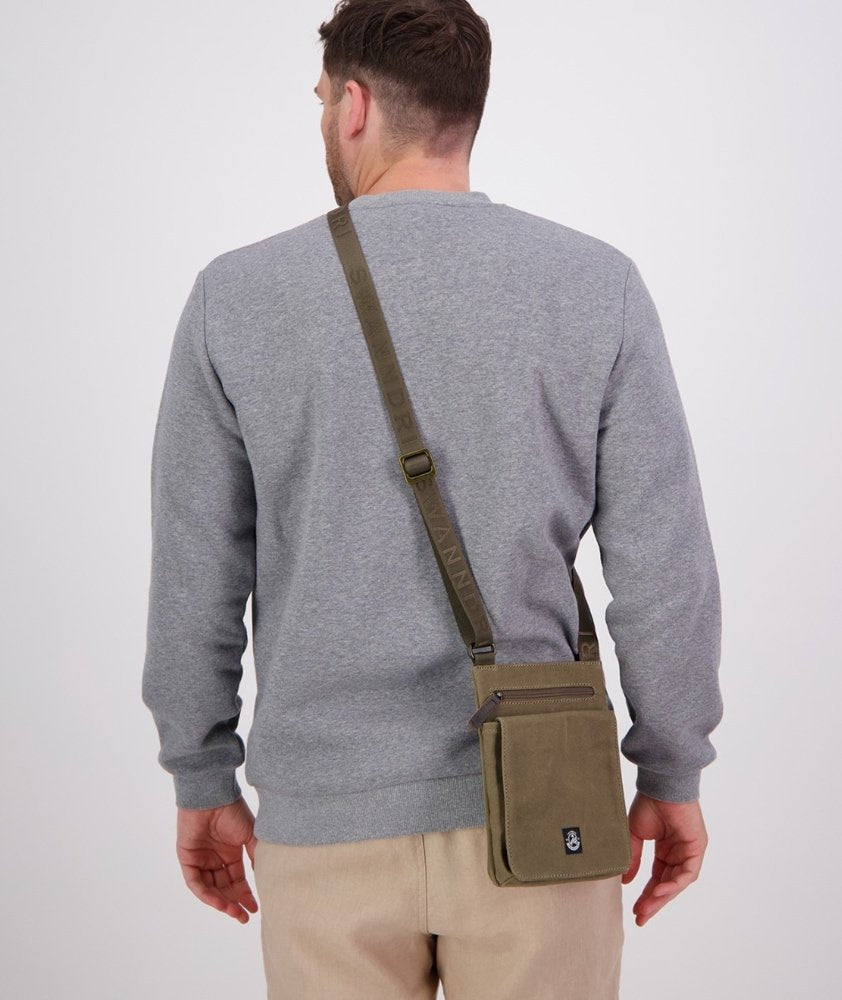 A man wearing a gray sweatshirt and beige pants, shown from the back, wearing an olive green canvas crossbody bag with a matching strap.