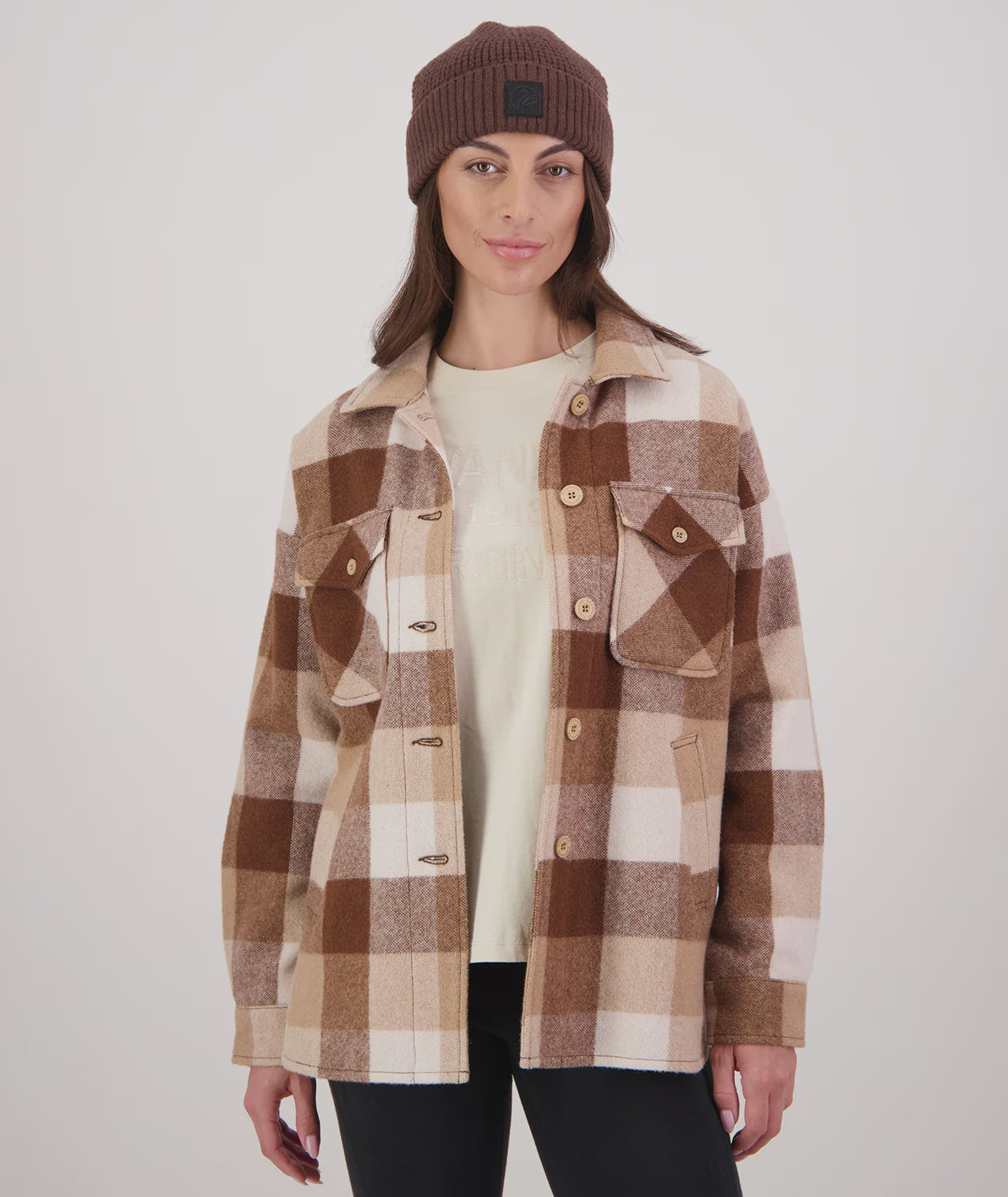 Woman wearing a plaid jacket and beanie on a white background