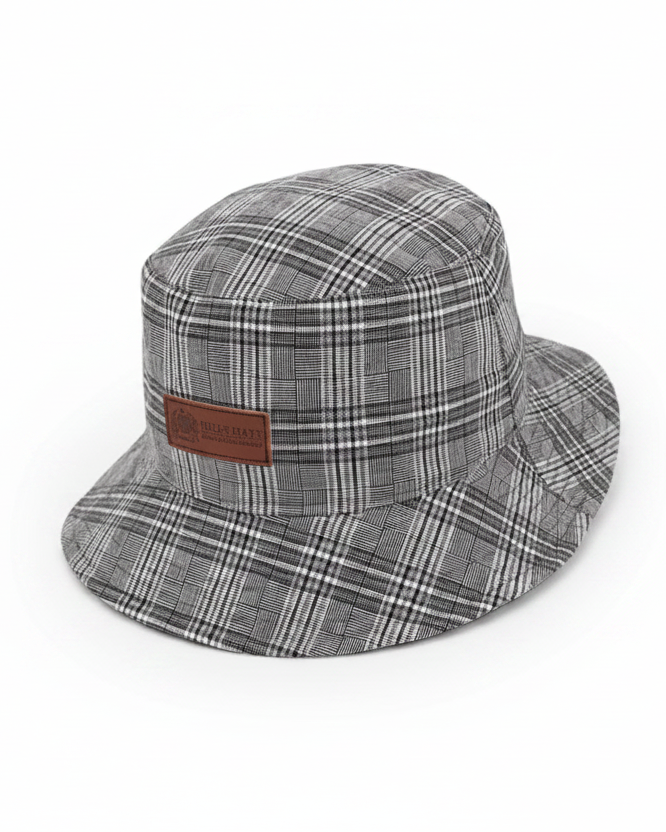 Plaid bucket hat with a brown leather patch on a light gray background
