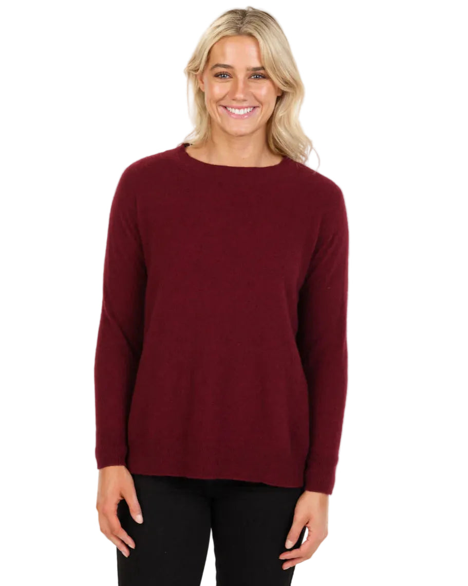 Woman wearing a cherry coloured sweater on a white background