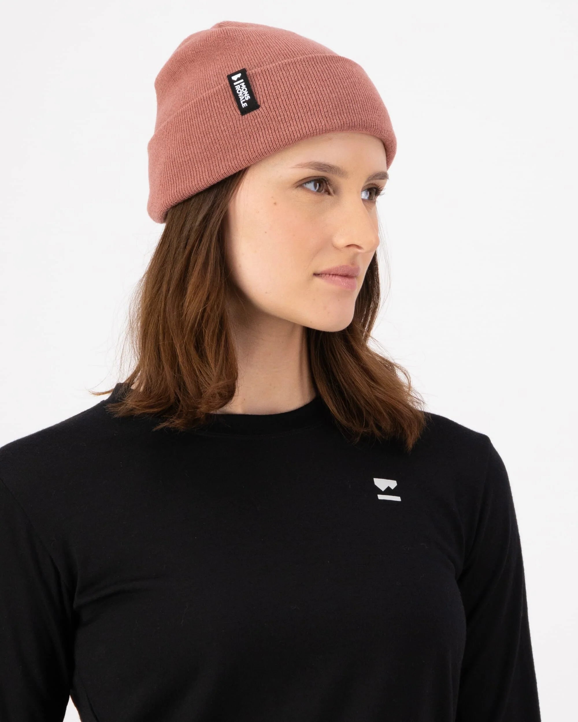 Person wearing a pink beanie with a logo and a black shirt with a logo on a white background