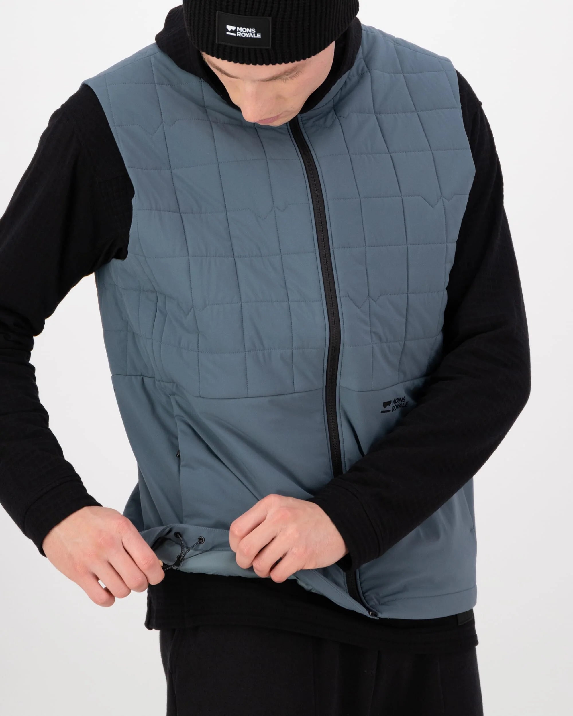 Person wearing a blue quilted vest over a black long-sleeve shirt on a white background