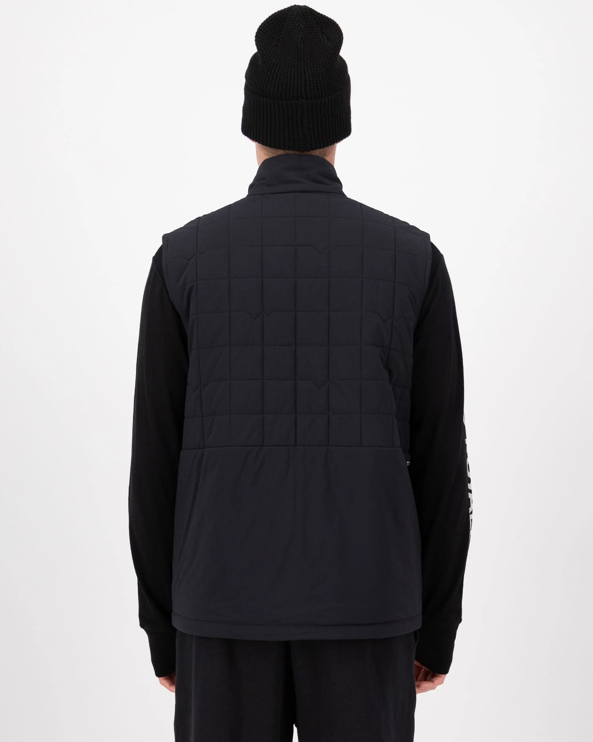 Person wearing a black quilted vest and black beanie on a white background