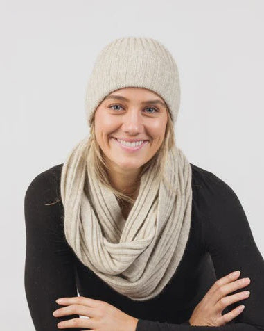 Woman wearing a beige knit hat and scarf on a white background