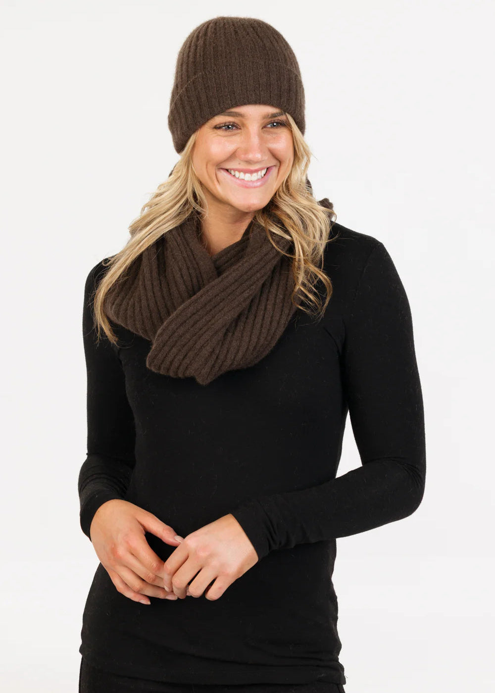 Woman wearing a cocoa knit hat and scarf on a white background
