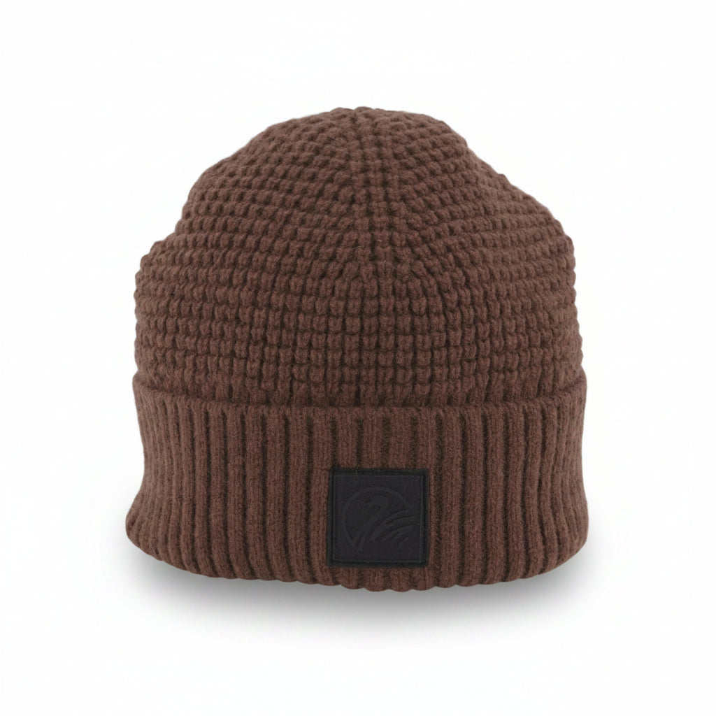 Brown knit beanie with a black patch on a light gray background