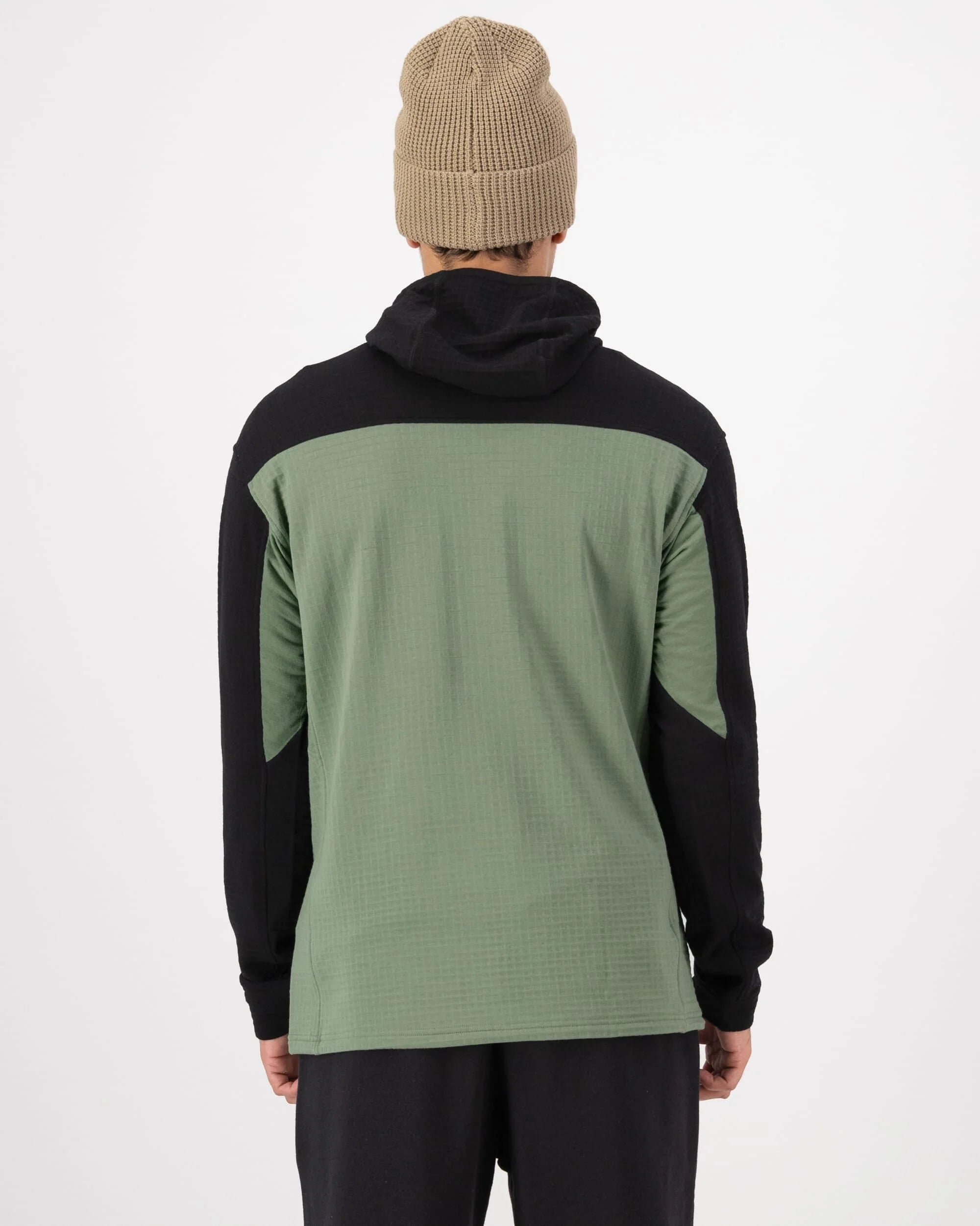 Person wearing a black and green jacket with a beige beanie on a white background