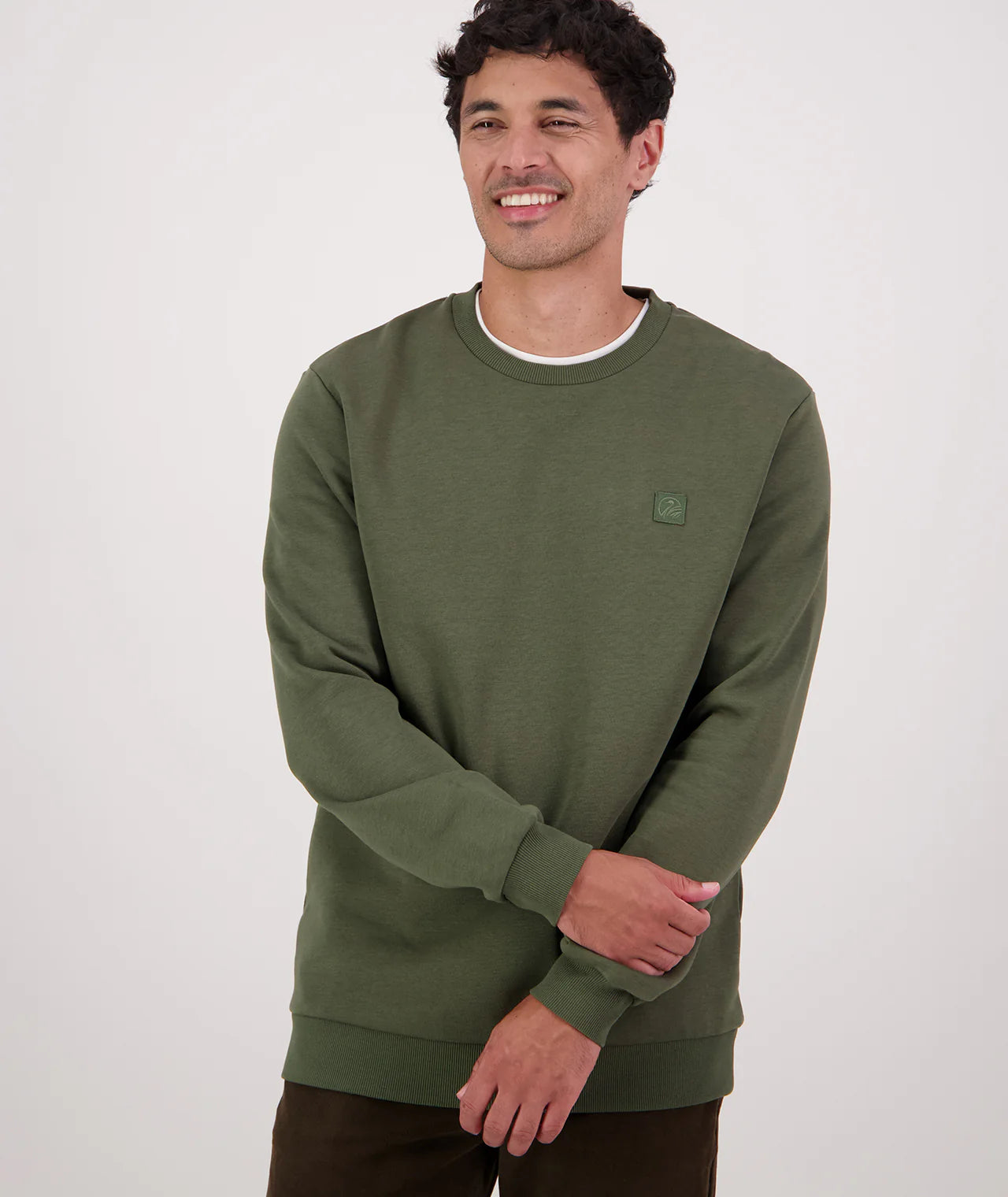 Man wearing a green sweatshirt with a small logo on a white background