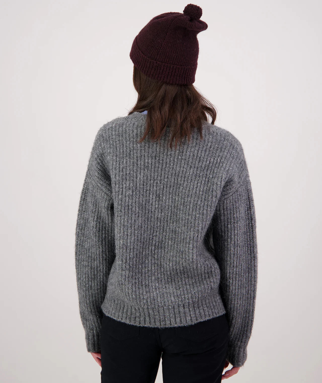 Person wearing a gray sweater and dark beanie from behind on a white background