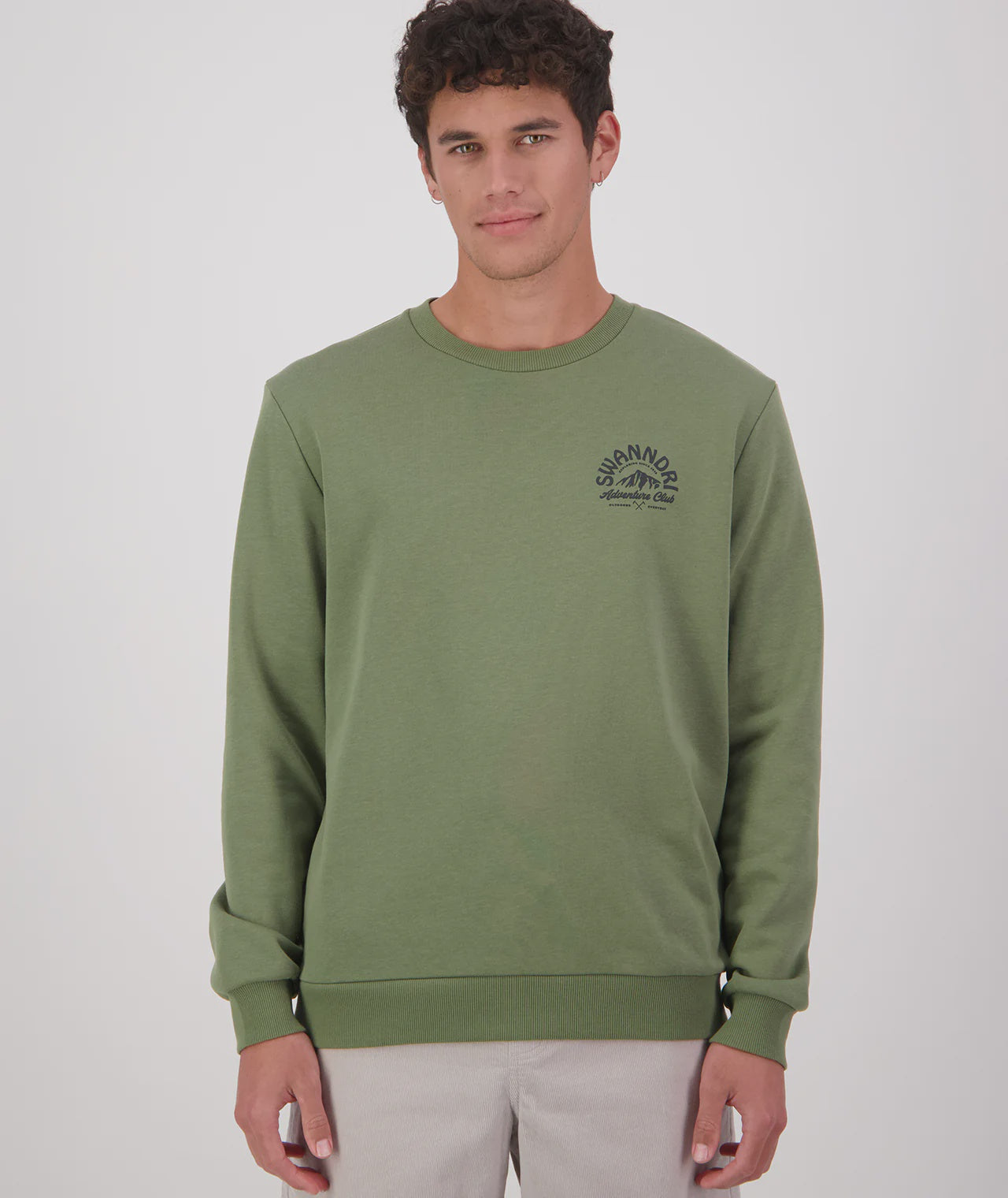 Man wearing a green sweatshirt with a brand logo on a light gray background