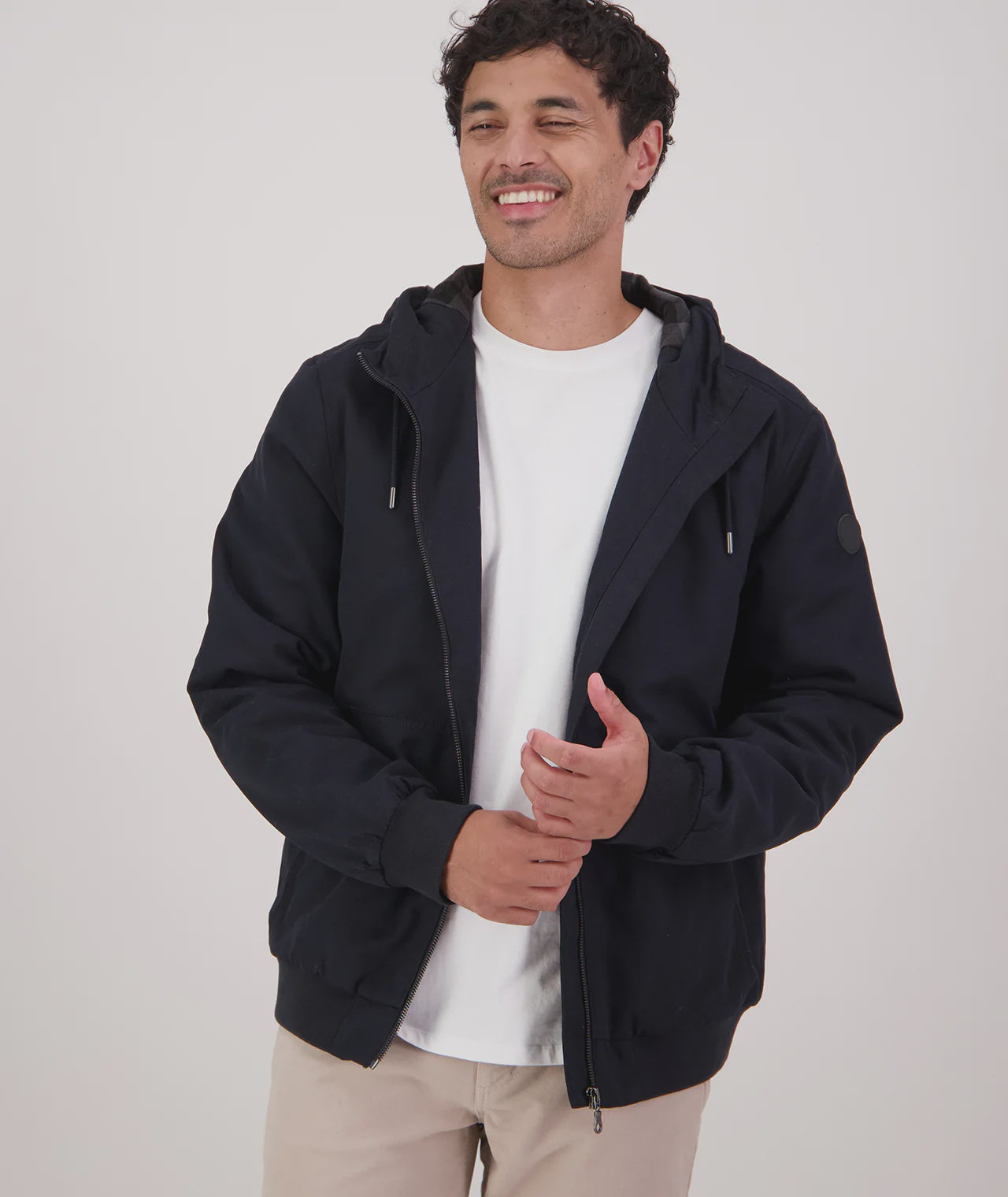 Man wearing a black hoodie over a white shirt on a white background