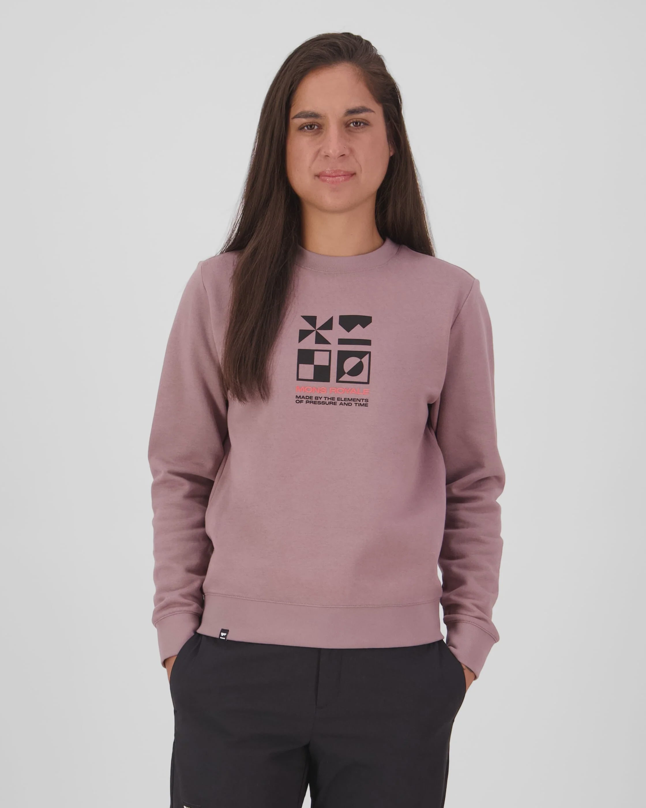 Person wearing a mauve sweatshirt with a Mons Royale logo on a white background