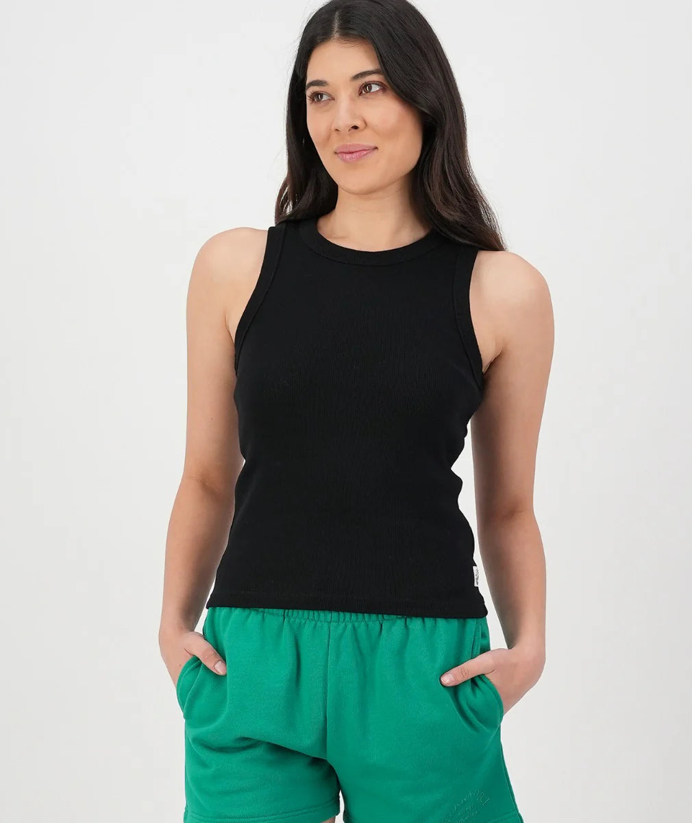 Woman wearing a black sleeveless top and green pants on a white background