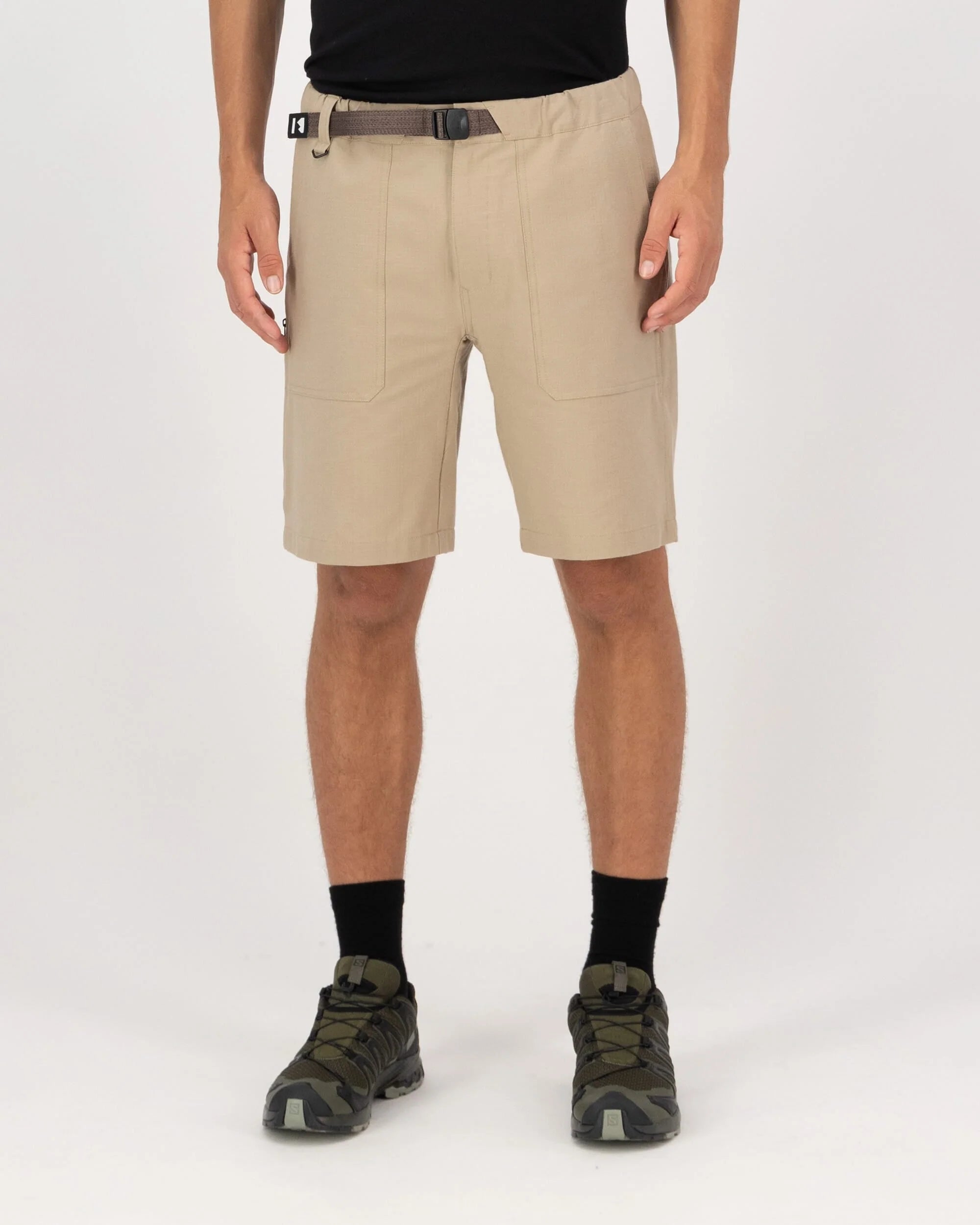 Person wearing beige shorts on a white background